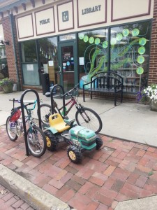 Children arrive on bikes and a tractor at the summer reading program 2015.